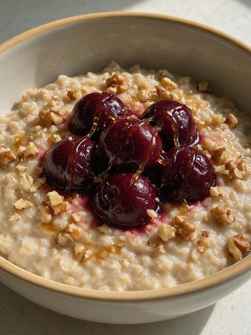 A bowl of tart cherry and honey bedtime oats, topped with cherries